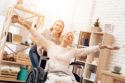 eldery woman in wheelchair smiling with young girl behind